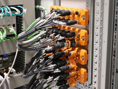 Dozens of connection cables run from four IO-Link modules mounted in a control cabinet