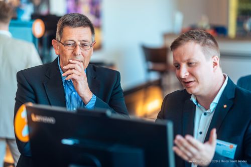 Foto: Zwei Personen stehen vor einem Monitor. Der ifm-Mitarbeiter Philipp Schmidkunz erklärt dem Kunden die Softwarelösung