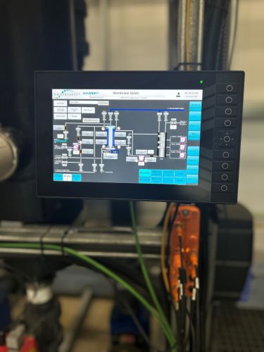 An HMI controller with water filtration process controls on the display with a visible orange ifm IO-Link master underneath.